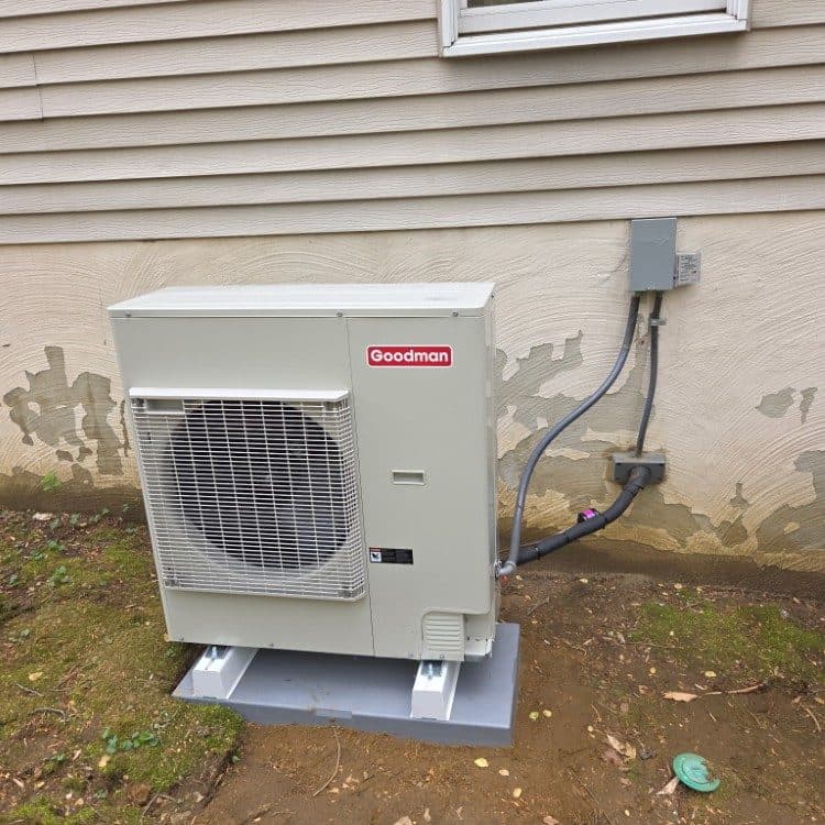Goodman heat pump installed on riser blocks and a composite pad with new electrical whip